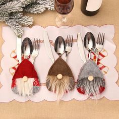 four spoons and two forks with santa hats on them, next to a bottle of wine