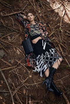 a woman is laying on the ground with her hand on her head and wearing boots