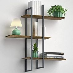 three shelves with books and plants on them against a white wall next to a lamp