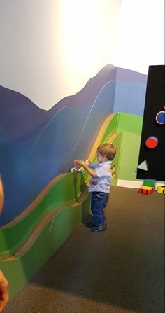 a little boy playing with toys in a play area at the children's museum