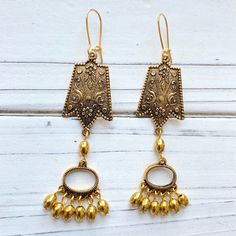 "Stunning floral chandelier earrings in sophisticated gold tones with two tiers that sway gracefully with movement. Earrings have a 3\" drop with gold plated, nickel free ear wires. These lightweight beauties will be the perfect finishing touch to complete your sophisticated look!" Long Drop Brass Chandelier Earrings, Gold Filigree Drop Flower Earrings, Gold Dangling Bead Jewelry, Gold Dangling Bead Earrings, Long Drop Brass Chandelier Earrings For Pierced Ears, Bohemian Bronze Chandelier Earrings With Ear Wire, Gold Dangle Jewelry With Beads, Gold Dangle Jewelry With Dangling Beads, Brass Filigree Dangle Plug Earrings