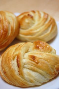 three croissants on a white plate sitting on a table