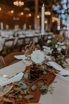 the table is set with white flowers and greenery for an elegant dinner or reception