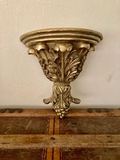 an ornate gold vase on top of a wooden trunk