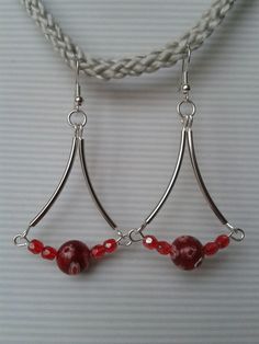 two red beads are hanging from silver hoop earrings