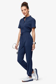 Now, this is modern. A jumpsuit! No easier way to get dressed – nothing to match and your top stays tucked in. Ours is so cute – a drawstring to add shape plus six functional pockets. The Easy Stretch Collection is designed for a modern look and easy fit. 4-way stretch performance fabric keeps you comfortable all shift long. • Modern fit • Open placket neckline • Concealed full-length front zipper • Drawstring waist • Total of 6 pockets • 2 roomy front patch pockets • 1 cellphone pocket • 2 back Fashionable Scrubs Woman, Nanny Uniform Modern, Medical Outfits Women, Modern Restaurant Uniforms, Nurse Ootd, Nurses Uniform Modern, Scrub Jumpsuit, Scrubs Uniform Cute, Nurse Fashion Scrubs