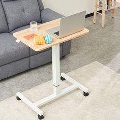 a laptop computer sitting on top of a wooden table next to a gray couch in a living room