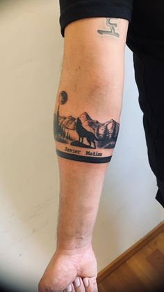 a man with a tattoo on his arm that has mountains and a wolf in it