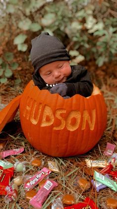 a baby in a pumpkin with the word hudson carved into it's face and surrounded by candy