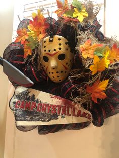 a hockey mask hanging on the front door with fall leaves around it and a sign that says camp crystal lake