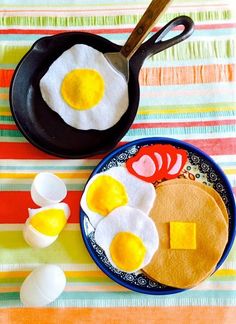 an egg and other food items are on a colorful table cloth next to a frying pan