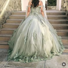 a woman in a green wedding dress standing on some steps with her back to the camera