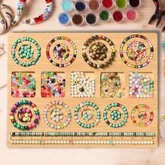 a wooden beaded board with beads and other crafting supplies laid out on the table