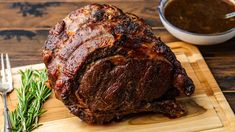 a large piece of meat sitting on top of a cutting board next to a fork and knife