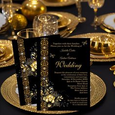 a black and gold wedding card on a table with plates, silverware and glasses