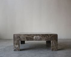 a marble coffee table sitting on top of a cement floor next to a white wall