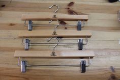 three wooden hangers with metal hooks on them