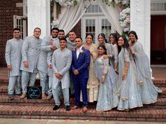 a group of people standing next to each other in front of a white and brick building