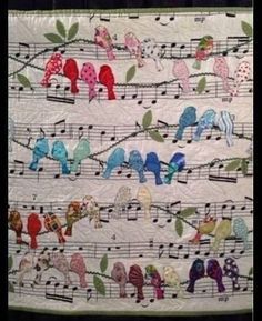 a quilted wall hanging with birds and music notes on it's sides,