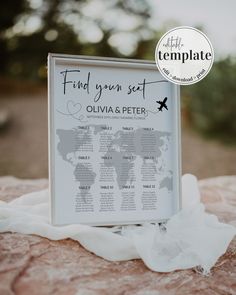 a wedding seating chart on top of a rock with a white sheet covering the table