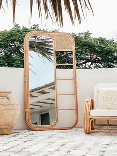 a mirror sitting on top of a wooden frame next to a chair and potted plant