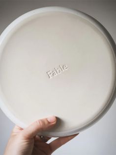 a person holding up a white plate with the word table on it's side