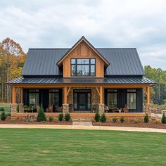 a large house with a metal roof in the middle of a grassy area next to trees