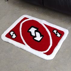 a red and white rug with arrows on the floor next to a black leather couch