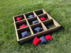 a tic tac toe game sitting in the grass with red and blue pillows