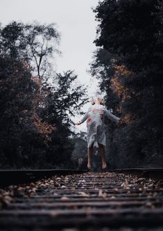 a person jumping on train tracks in the woods