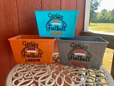 three different colored plastic containers sitting on top of a metal table