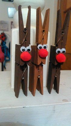 two wooden reindeers with red noses and brown nose are hanging from the side of a refrigerator