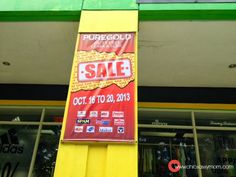 a sale sign hanging from the side of a yellow pole in front of a store