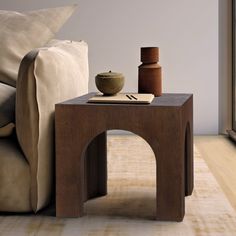 a wooden table with a vase on it next to a couch and window sill