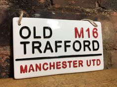 a white sign that says old traford manchester utd hanging on a brick wall