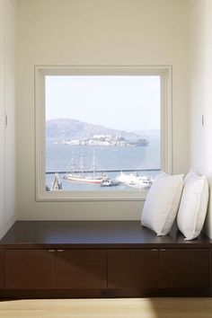 there is a window in the room with two pillows on it and a boat out front