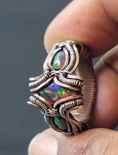 This exquisite black opal ring is a true masterpiece, featuring a mesmerizing array of multiple stones that showcase the natural beauty of this precious gemstone. Handcrafted with care and attention to detail, this one-of-a-kind piece is sure to impress anyone who sees it. The stones display a stunning range of colors, including deep blues, purples, greens, and oranges, all perfectly complementing each other in a dazzling display of natural beauty. The ring itself is made from high-quality mater Black Opal Cabochon Ring As Gift, Handmade Black Opal Jewelry, Black Opal Ring With Cabochon As A Gift, Oval Black Opal Jewelry, Black Oval Opal Jewelry, Multicolor Opal Gemstone Ring, Black Cabochon Opal Ring, Black Opal Round Jewelry, Unique Multicolor Opal Gemstone Ring