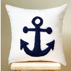 a white pillow with an anchor on the front and blue thread work on the back