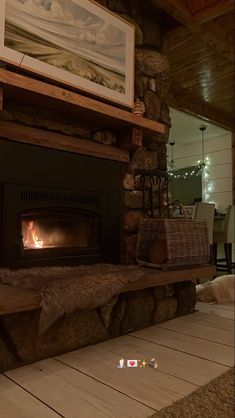 a fire place in the middle of a living room with wood flooring and stone fireplace