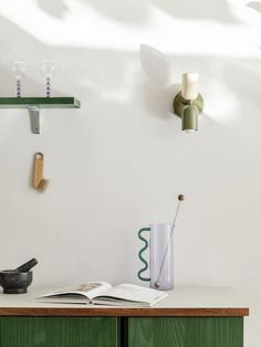 an open book sitting on top of a wooden table next to a vase and candle holder