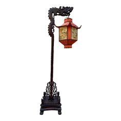 an old fashioned street light with a dragon on it's arm and a red lantern hanging from the side