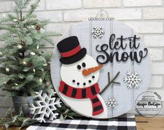 a wooden sign that says let it snow with a snowman on the front and side