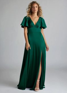 a woman in a green dress posing for the camera with her hands on her hips