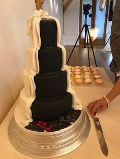 a large wedding cake sitting on top of a table next to a knife and cupcakes