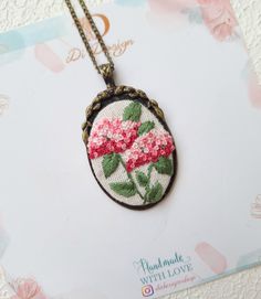 a close up of a necklace on a card with flowers in the middle and one flower hanging from it