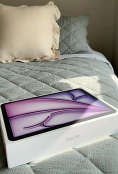 an iphone box sitting on top of a bed next to a pillow and throw pillow