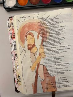 an open bible with watercolors on it