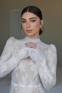 a woman wearing a white dress and posing for the camera with her hands on her chest