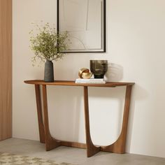 a wooden table topped with a vase filled with flowers next to a framed photograph on the wall