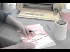 a person is using a machine to cut paper on a table next to a coffee cup